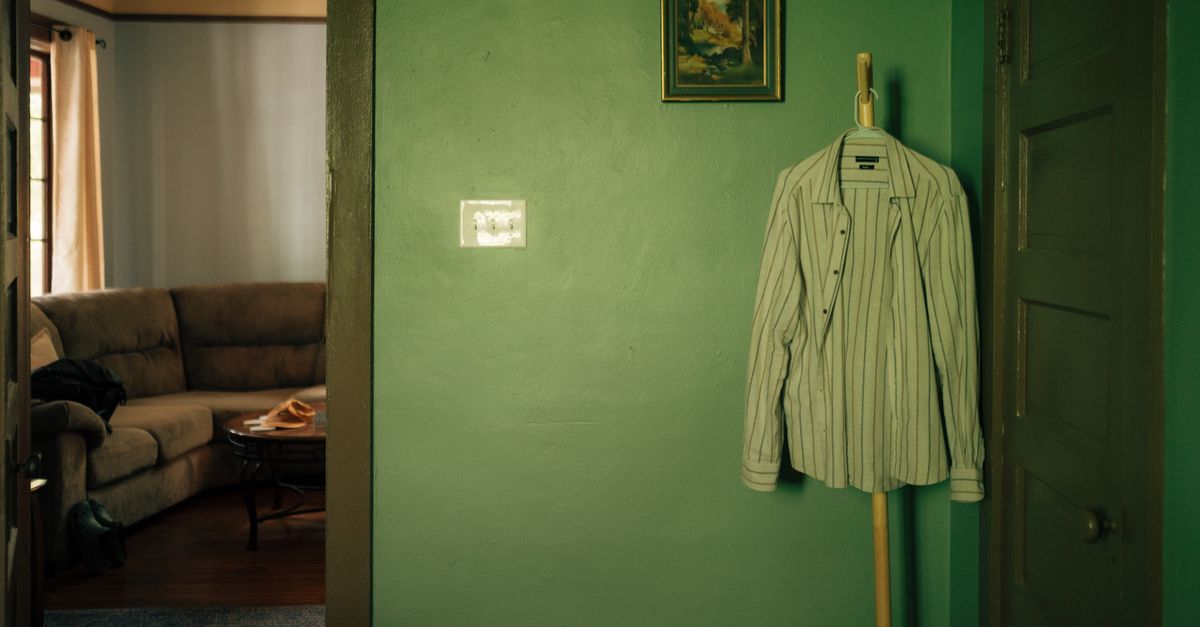 A minimalist interior shot featuring a striped shirt hanging on a green wall in Gainesville, FL.